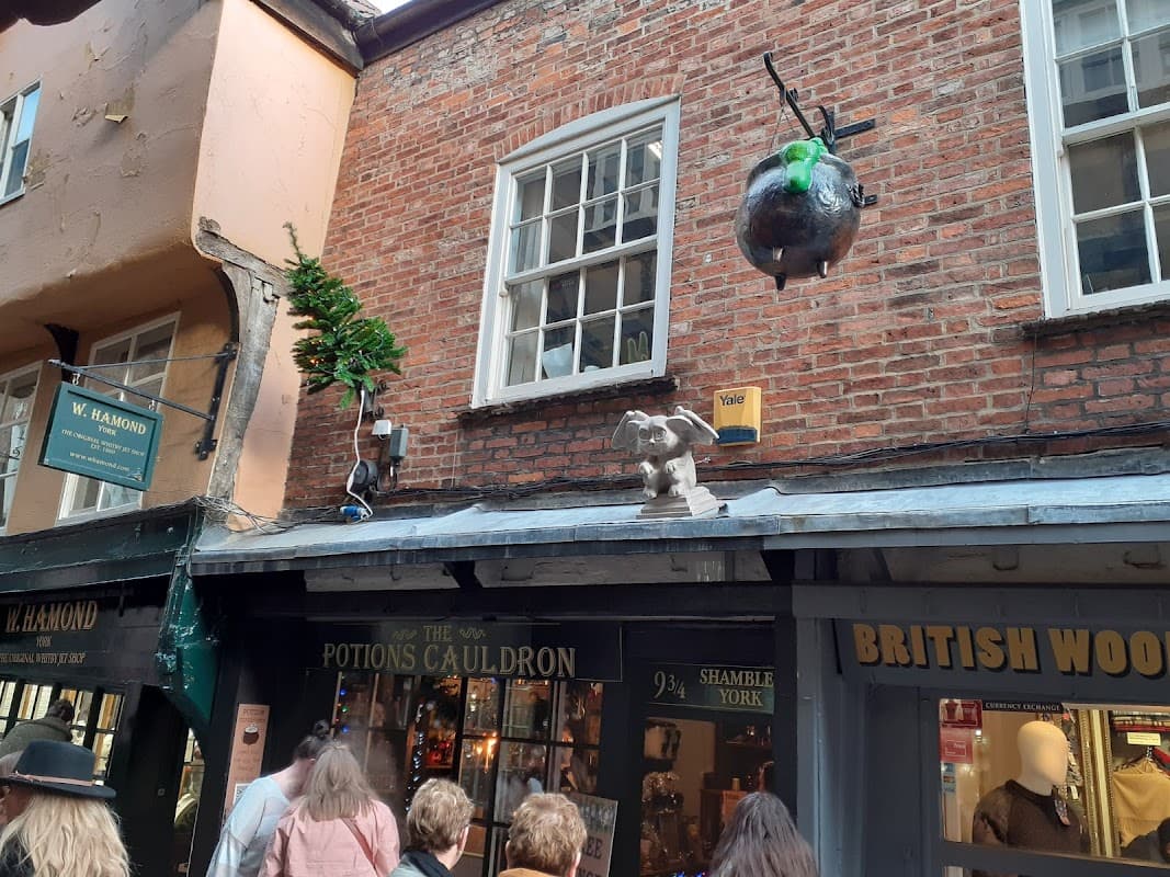The Potions Cauldron shop front with a whimsical cauldron and elephant statue, set in a historic York street.