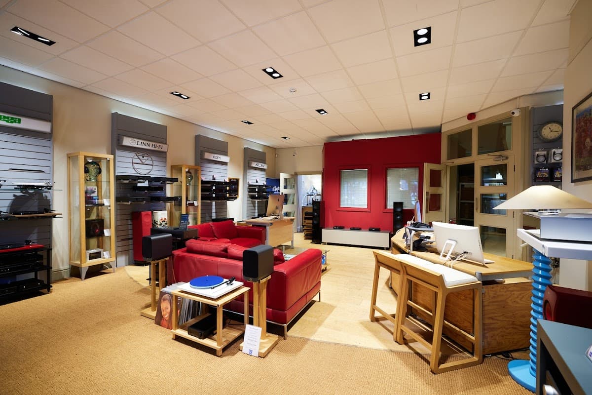 Modern homeware store interior featuring red seating, audio equipment displays, and a workspace with a computer.