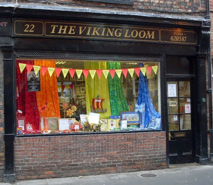 Colorful window display with fabric drapes, homeware items, and decorative banners at The Viking Loom in York.