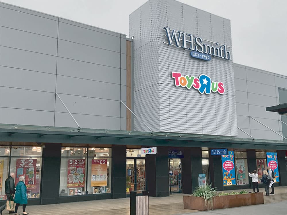 Toys R Us storefront featuring colorful signage, with WHSmith above and promotional posters in windows.