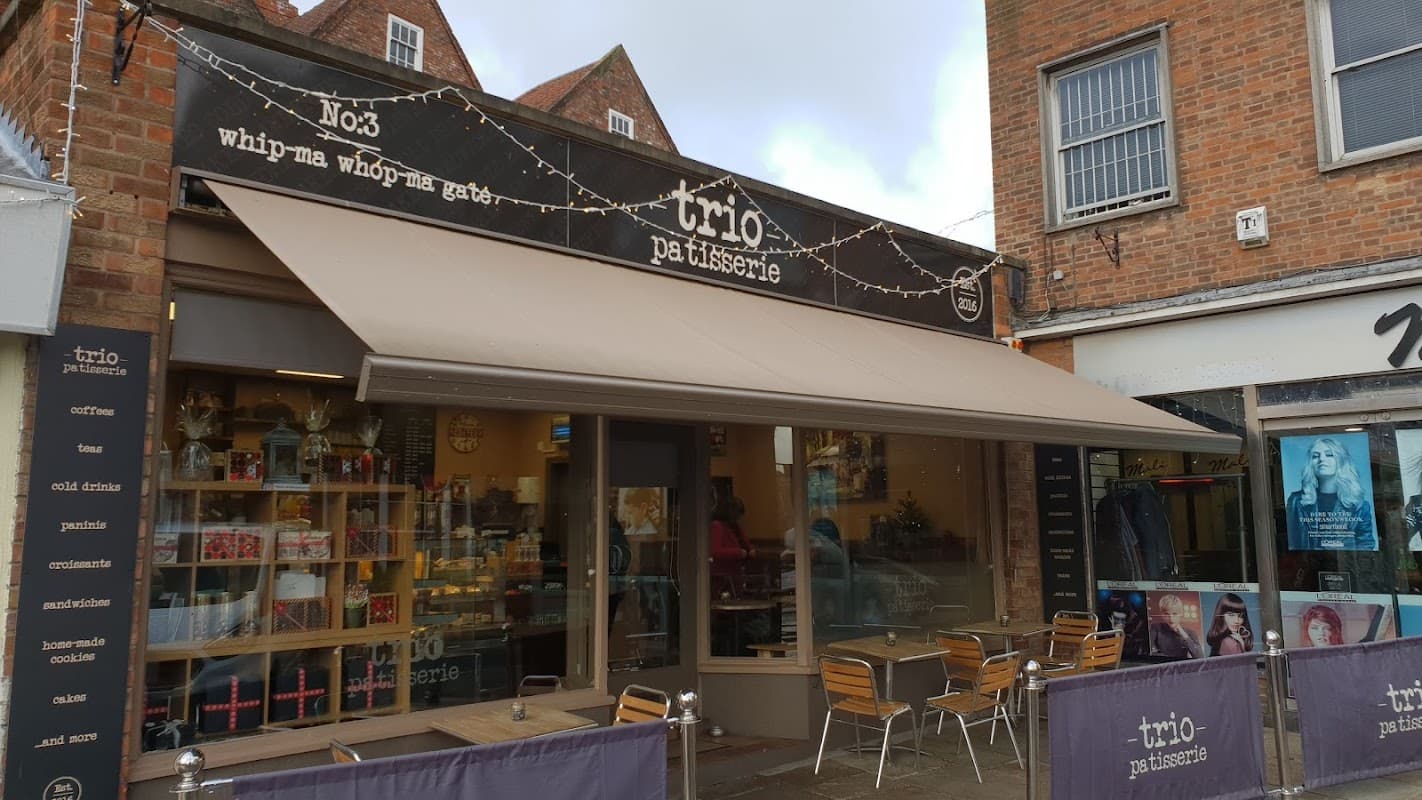 Charming bakery exterior with a retractable awning, outdoor seating, and a sign reading "Trio Patisserie" in York.
