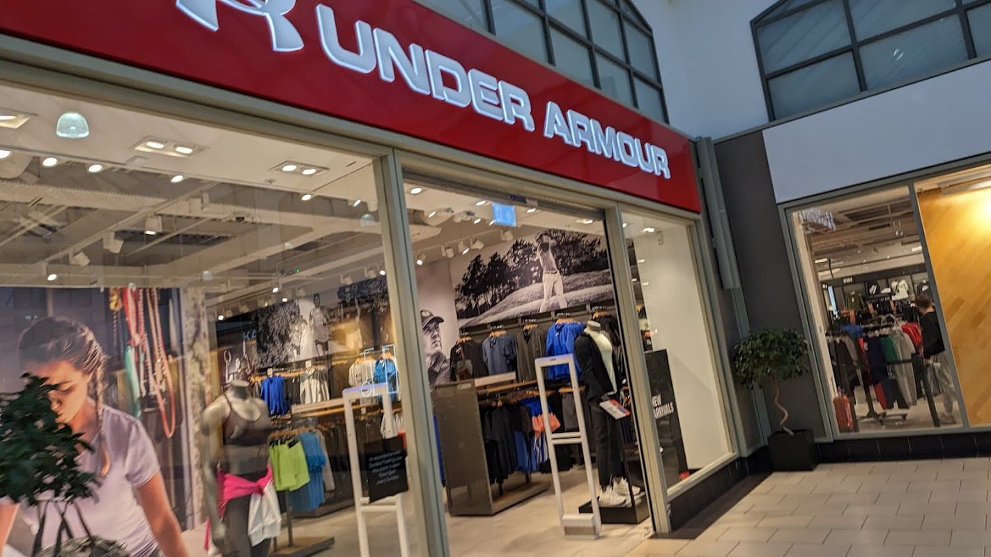 Under Armour store entrance featuring athletic apparel and gear, with a modern design and bright signage.