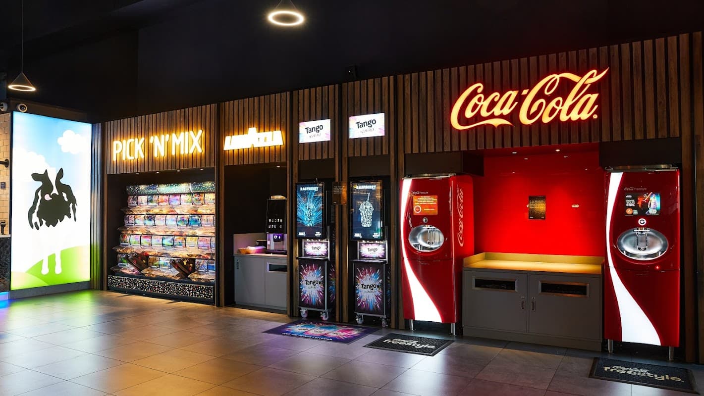 Brightly lit concession area featuring a Pick 'N' Mix stand and Coca-Cola vending machines.