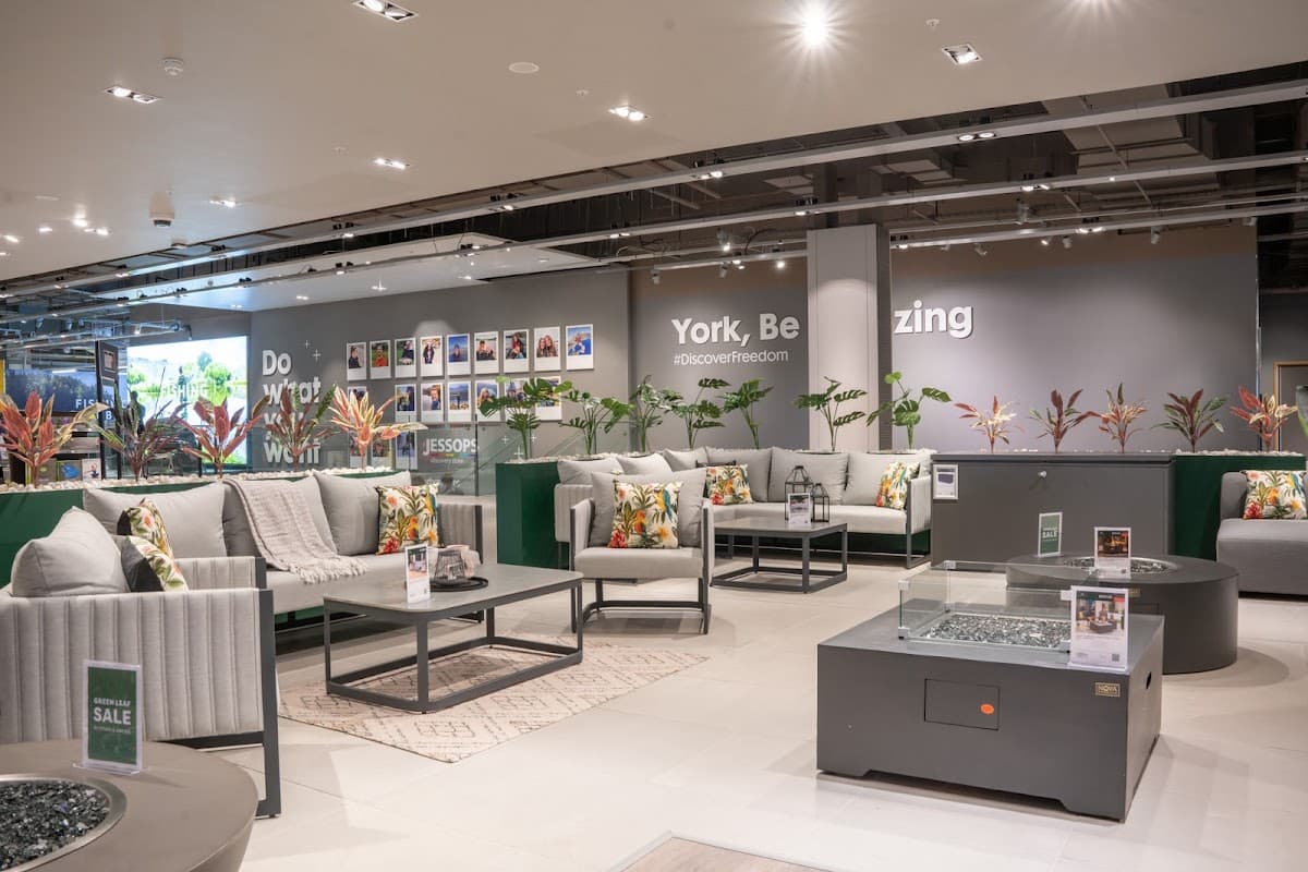 Modern garden furniture display featuring stylish sofas and tables, adorned with vibrant cushions and plants.