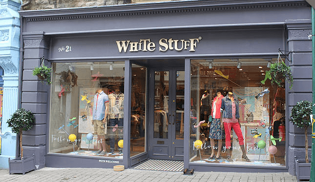 Storefront of White Stuff in York, featuring colorful clothing displays and decorative plants outside.