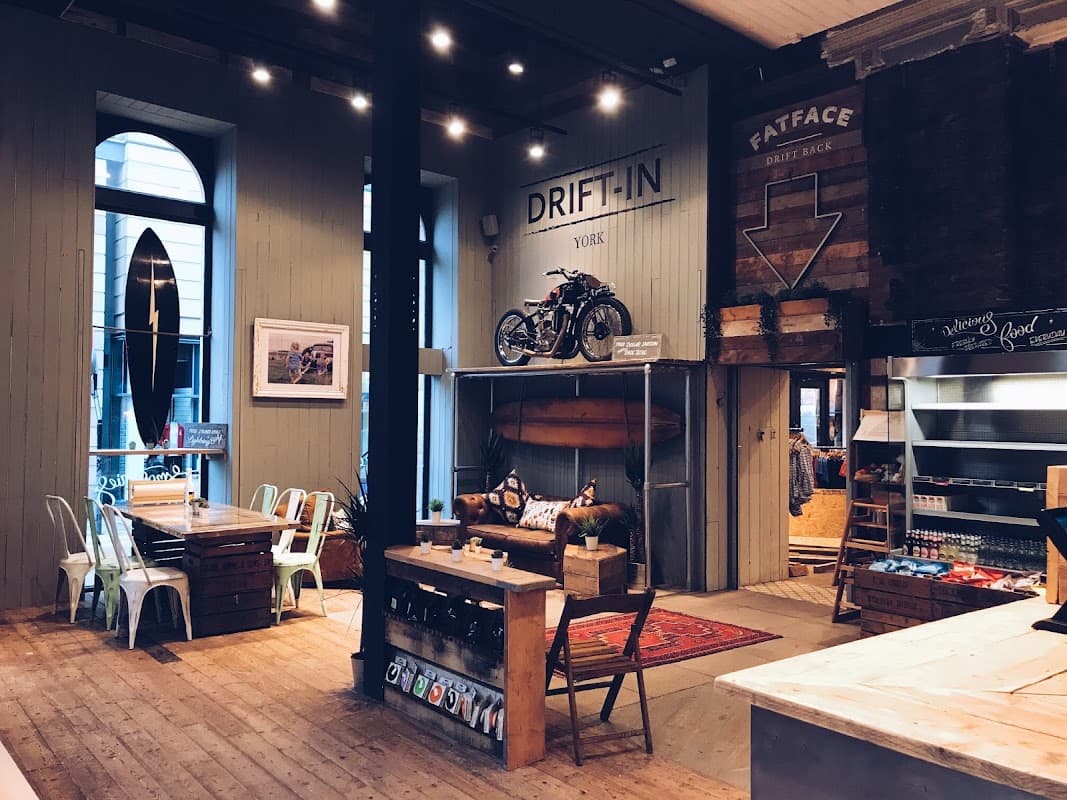 Cozy cafe interior with wooden floors, surfboards, a vintage motorcycle, and rustic furniture.