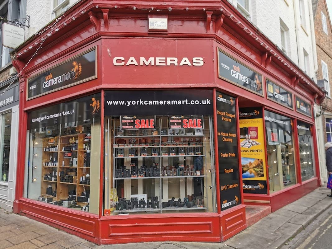 Red storefront of York Camera Mart featuring cameras, accessories, and a sale sign, located in York, Yorkshire.