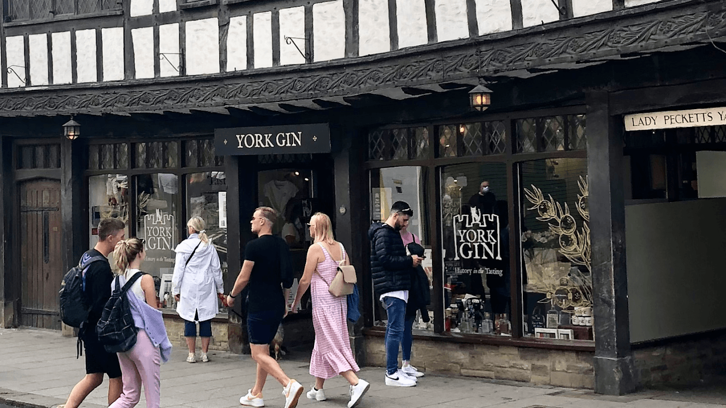 York Gin shop exterior with people walking by, showcasing traditional architecture and displays of gin products.