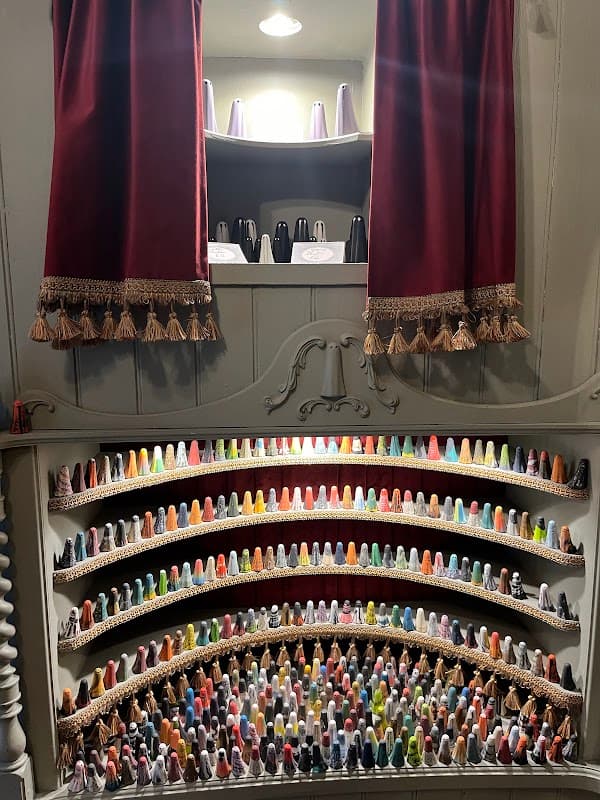 Colorful display of miniature gift items arranged in a tiered shelf, with red curtains framing the scene.
