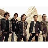 Band named "Journey" standing outdoors, wearing casual and leather jackets, with rocky landscape in the background.