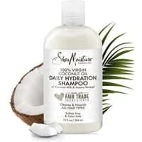 Shea Moisture coconut oil shampoo bottle with palm leaf and cracked coconut background.