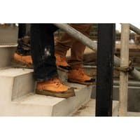 Tan leather Amblers Safety Fs226 boots with black toe caps, rugged soles, and lace-up design, worn on concrete steps.