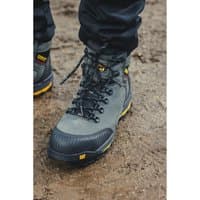 Gray Caterpillar Munising safety boot, size 11, with black laces, yellow accents, and rugged sole on muddy ground.