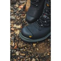 Black Caterpillar waterproof safety boots with reinforced toe, metal eyelets, and rugged sole on rocky ground.