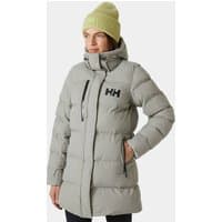 Grey Helly Hansen women's puffy parka with high collar, front zipper, and HH logo on chest, worn by model in green beanie.
