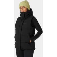 Black Helly Hansen women's puffy vest with high collar and front zipper, worn by a model in a light green beanie.
