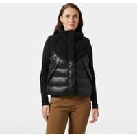 Black Helly Hansen women's down vest with high collar, quilted design, and front zipper, worn over a black long-sleeve shirt.
