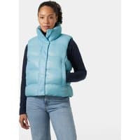 Blue Helly Hansen women's puffer vest, high collar, sleeveless, quilted design, worn over a dark long-sleeve shirt.