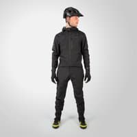 Black Endura Men's SingleTrack one-piece suit with hood, full zip, and gloves, worn with a helmet and neon-accented shoes.