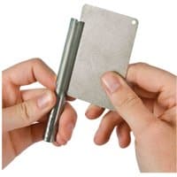 Credit card-sized diamond sharpening stone with a textured surface, held in hand next to a cylindrical tool.