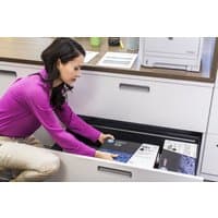 HP 05X black toner cartridge box with blue accents, placed in an office drawer near a printer.