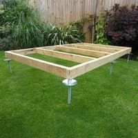 Wooden frame on metal adjustable supports for shed base on grass.