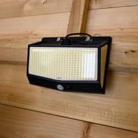 Black rectangular Shed Solar Light with LED panel and motion sensor, mounted on wooden wall.