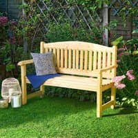 Wooden garden bench with slatted backrest and armrests, natural finish, set on grass with decorative pillows.