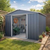 Anthracite metal shed with sliding doors, gabled roof, and garden tools inside, set in a grassy yard with potted plants.