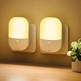 White plug-in night lights with warm glow, oval shape, adjustable brightness, and dusk to dawn sensor, set of two.