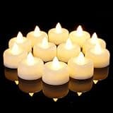 12 white flameless LED tea lights with warm yellow glow, arranged in a circle on a reflective black surface.