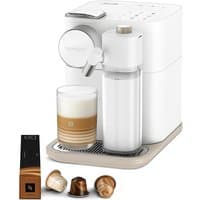 White Nespresso Gran Lattissima coffee machine with milk frother, cup of layered coffee, and three capsules.