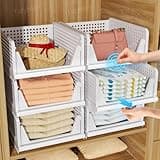 White stackable plastic drawer organisers with open fronts, holding folded clothes and accessories in a wooden wardrobe.