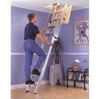 Werner Deluxe Stairway Loft Ladder, silver with handrails, extending from ceiling hatch, used by person in blue jeans.