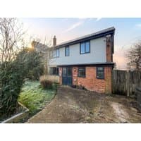 Two-story brick and siding house with blue door, large windows, and frosty garden path in winter morning light.