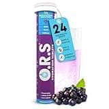 O.R.S Electrolytes Tablets in purple tube with blackcurrant flavor, glass of pink drink, and blackcurrant berries.