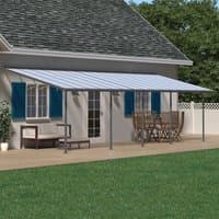 Grey Palram Canopia Sierra patio cover with clear roof panels, attached to house, over wooden deck with outdoor furniture.