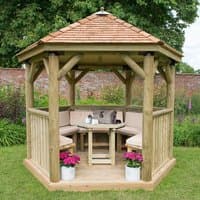 Luxury wooden garden gazebo with New England cedar roof, furnished seating for 10, surrounded by greenery.
