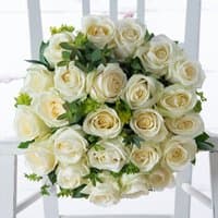 Bouquet of 12-24 white roses with green leaves, arranged in a round shape on a white chair.