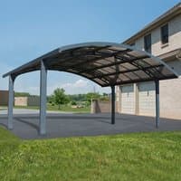 Grey metal double carport with curved roof and open sides, designed for two vehicles, set on a paved driveway.