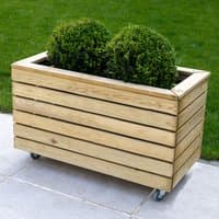 Wooden garden planter with horizontal slats, two green shrubs, and wheels for mobility, measuring 2'7 x 1'4.