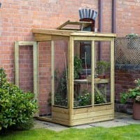 Wooden lean-to greenhouse with open back, clear panels, and slanted roof, attached to a brick wall.