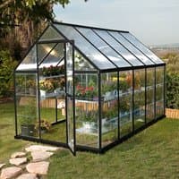 Grey polycarbonate greenhouse with clear panels, pitched roof, and open door, showcasing plants inside.
