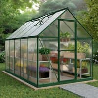 Green-framed polycarbonate greenhouse with clear panels, pitched roof, and walk-in door, surrounded by garden.