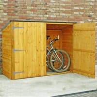 Wooden bike shed with double doors, sloped roof, and no floor, housing a bicycle against a brick wall.
