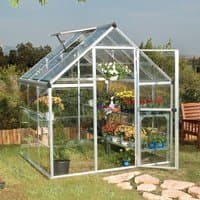 Silver polycarbonate greenhouse with clear panels, pitched roof, open door, and interior shelves filled with plants.