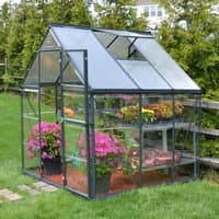 Grey polycarbonate greenhouse with sloped roof, clear panels, and metal frame, housing plants and flowers inside.