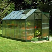 Green-framed polycarbonate greenhouse with sloped roof, clear panels, and open door on grassy lawn.
