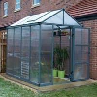 Grey 6x8 Palram Canopia Glory greenhouse with clear panels, pitched roof, and open door, set on a grassy area.