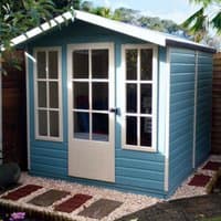 Blue wooden summerhouse with white-framed windows and door, pitched roof, and pebble path in garden setting.